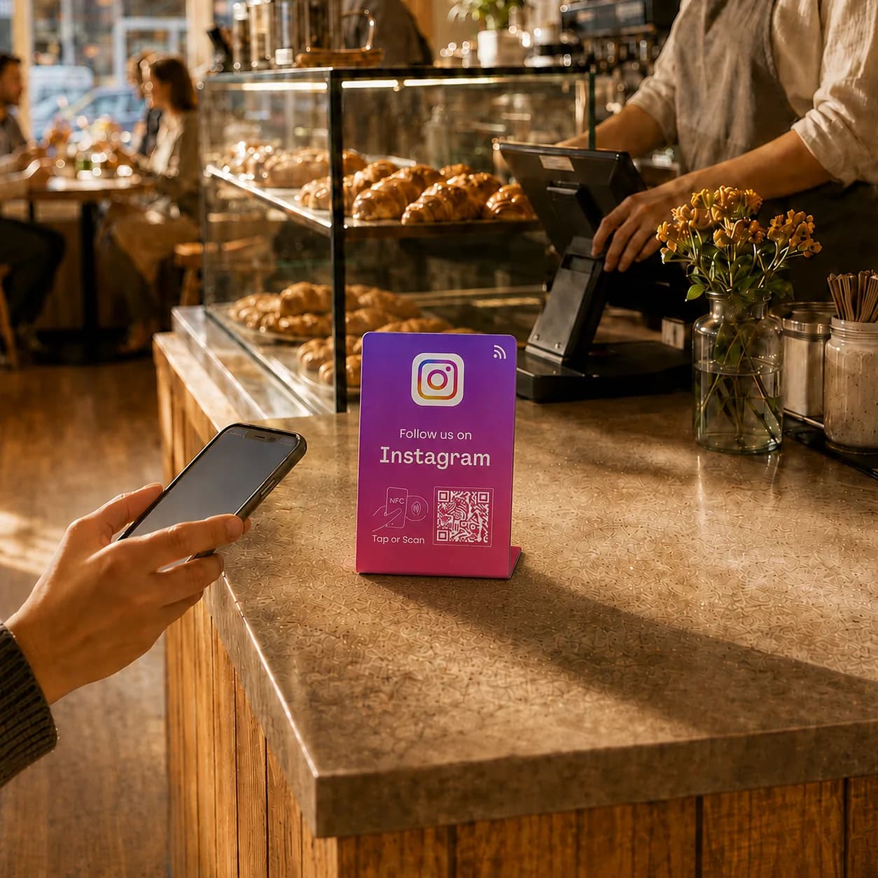 Purple Leovo Instagram follow card standing on a cafe counter beside a customer holding a phone.